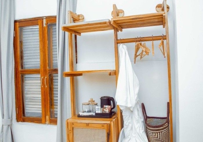 A room with a closet , a table , a chair and a window.
