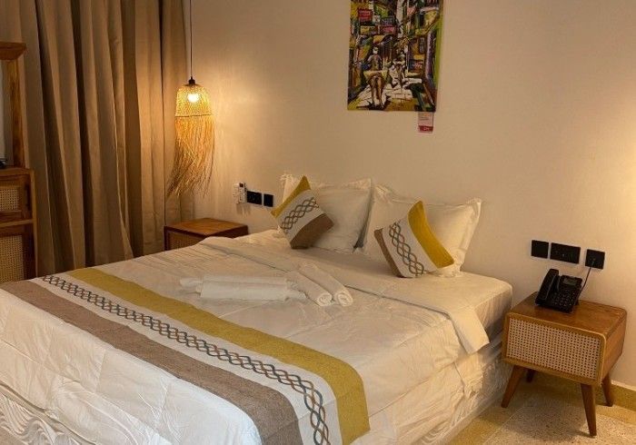 A hotel room with a bed , nightstand , lamp and painting on the wall.