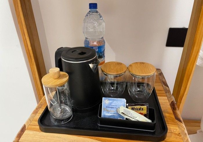 A tray with a kettle , cups , sugar and a bottle of water on it.
