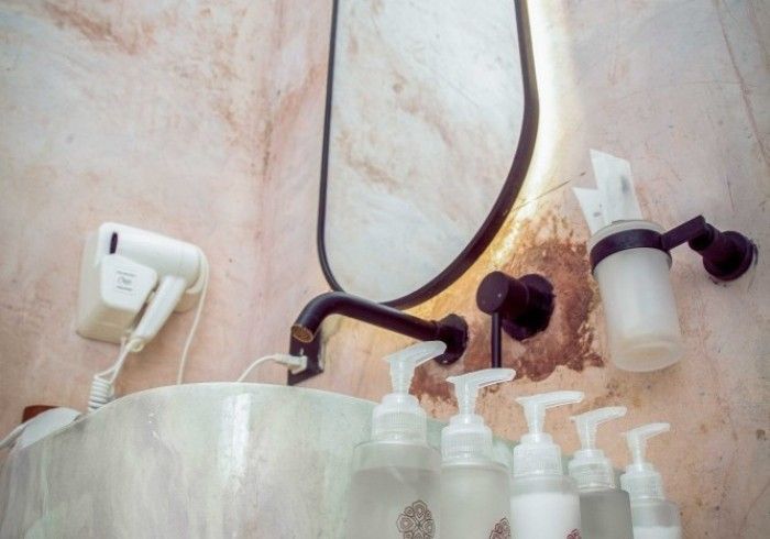 A bathroom with a sink , mirror , soap dispensers and a hair dryer.