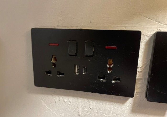 A black electrical outlet is sitting on a white wall.