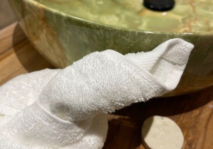 A person is holding a white towel in front of a sink.
