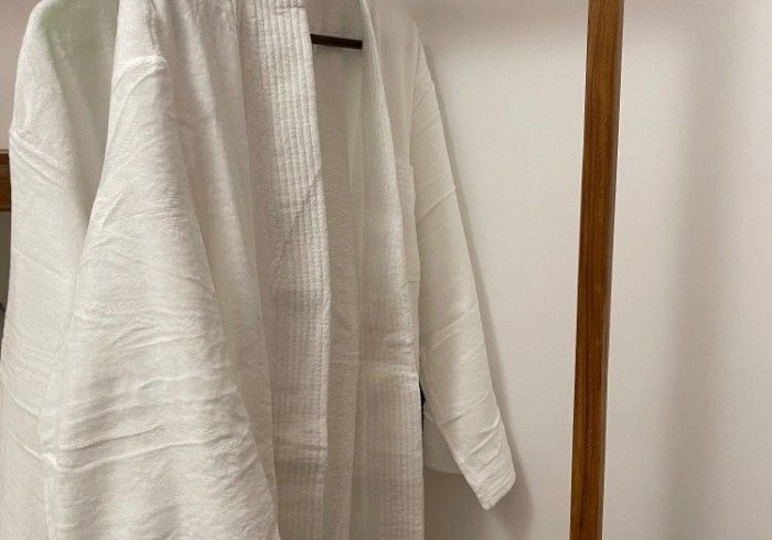 A white robe is hanging on a wooden rack.