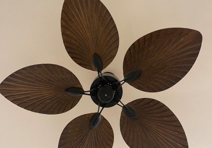 A ceiling fan with wooden leaves on it