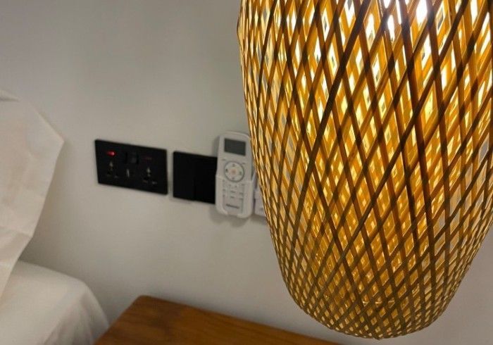 A phone is plugged into a wall next to a lamp