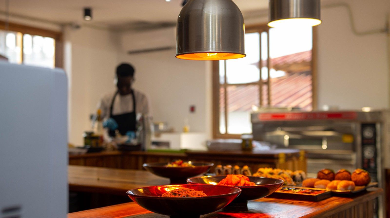 A man in an apron is standing behind a counter in a kitchen.
