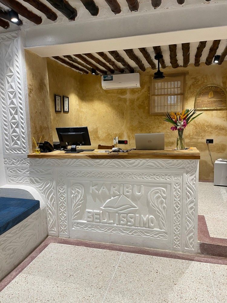 A reception desk with a computer and a vase of flowers on it.