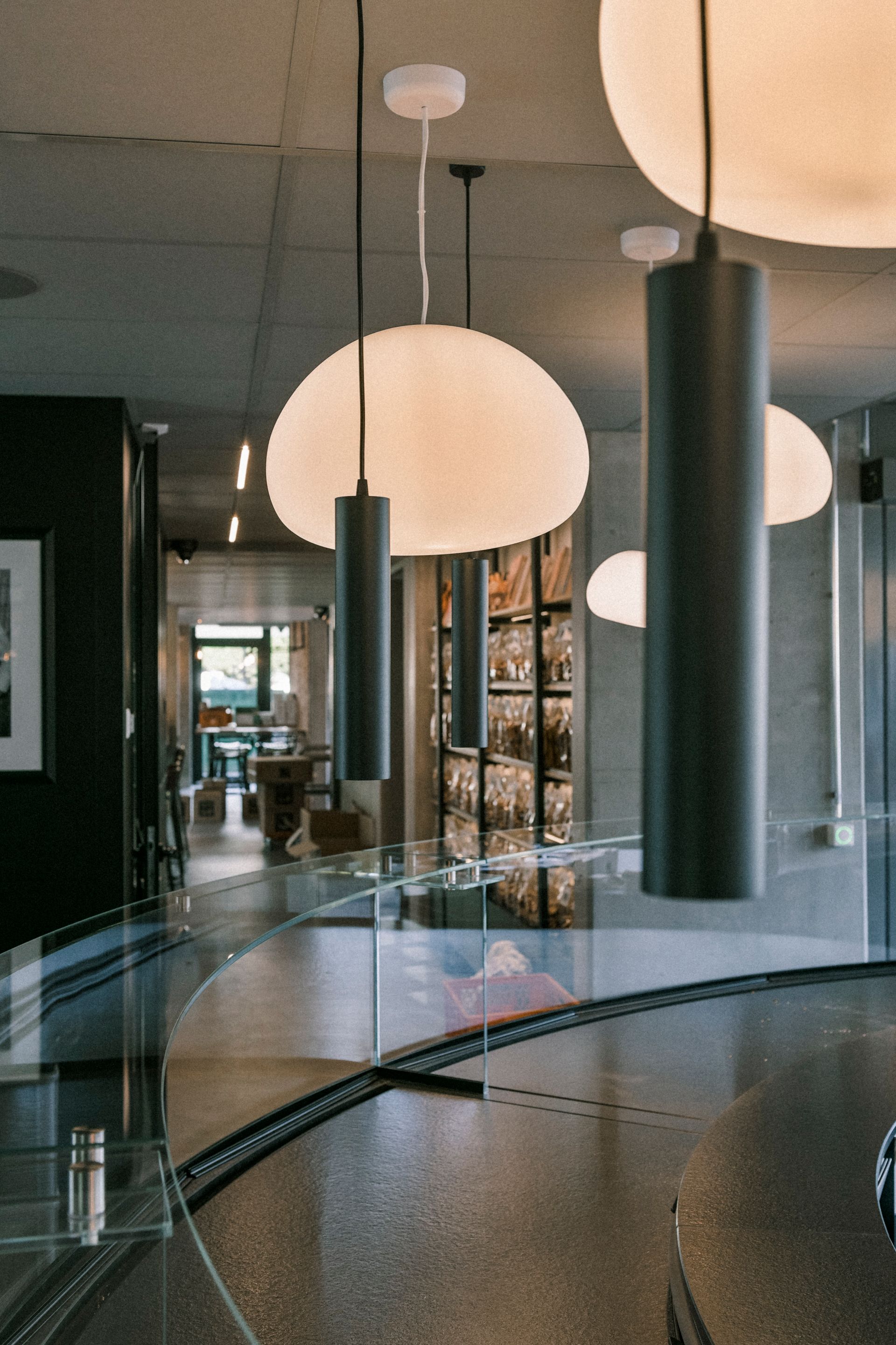 Intérieur de bar moderne avec comptoir incurvé, suspensions et plafond en béton.