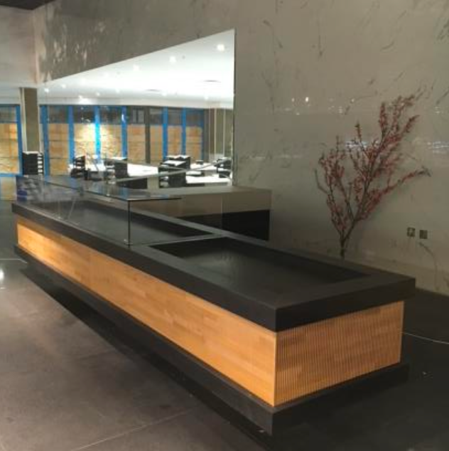 Un long comptoir en bois avec un plateau en verre, peut-être destiné à l'exposition.