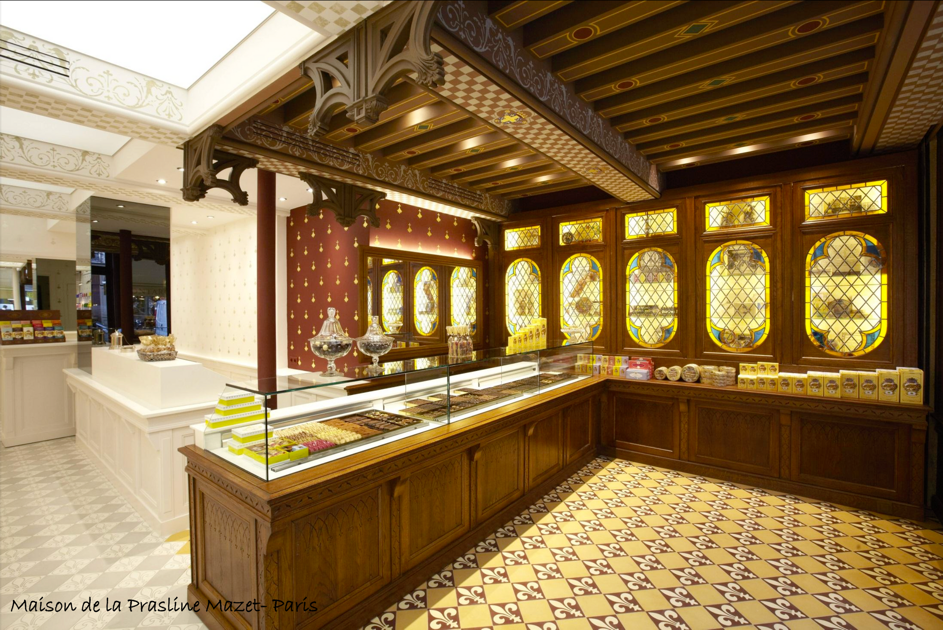 Intérieur d'une confiserie avec boiseries, vitrines en verre et plafond orné.