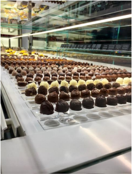 Vitrine avec rangées de chocolats noirs et blancs assortis.