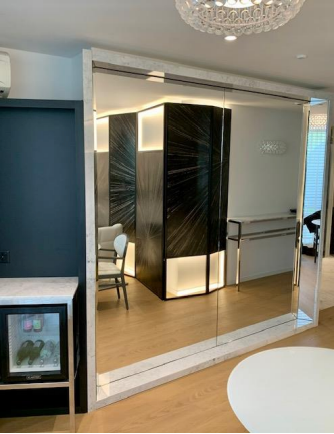 Cloison de séparation en miroir avec panneaux géométriques noir/blanc, petit réfrigérateur et table blanche.