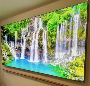 Grand écran affichant une scène de cascade vibrante avec de l'eau bleue et un feuillage vert luxuriant.