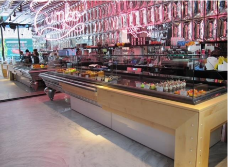 Intérieur de pâtisserie avec présentoirs de nourriture, néons et chrome brillant.