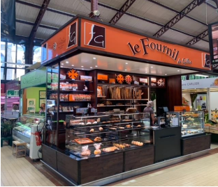 Stand de boulangerie "le Fournil" sur un marché, avec des produits de boulangerie exposés, signalétique marron et orange.