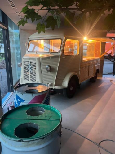 Camion-restaurant couleur crème, garé à l'intérieur. Des lumières vives illuminent les vitrines.