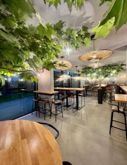 Intérieur de restaurant avec tables en bois, tabourets de bar.