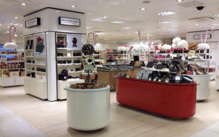 Intérieur d'une chocolaterie avec divers étalages de produits chocolatés. Touches blanches et rouges ; éclairage intense.