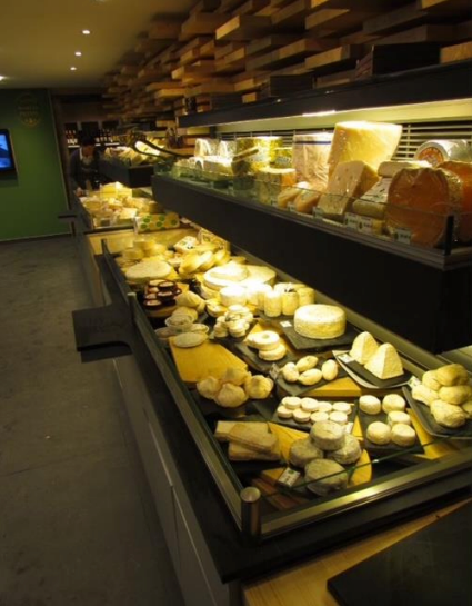 Vitrine de fromages sur un marché, présentant divers fromages.