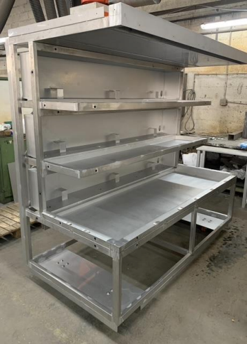 Poste de travail en métal avec plusieurs étagères et un plan de travail, dans un environnement atelier.