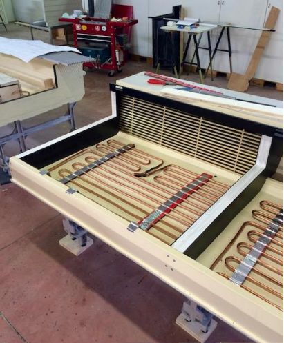 Un système de chauffage radiant partiellement construit avec des tubes en cuivre dans un cadre en bois.