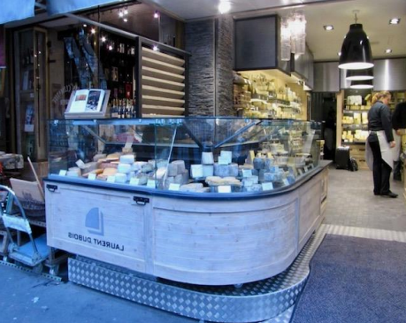 Fromagerie avec une vitrine remplie de fromages ; une personne se tient derrière le comptoir.