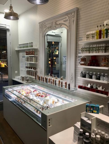 Intérieur de magasin de crème glacée avec vitrine en verre, miroir et étagères de produits.