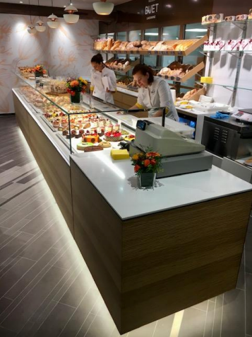 Intérieur de boulangerie avec deux employés, exposition de viennoiseries et de pains.