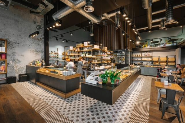 Intérieur de boulangerie moderne avec comptoirs d'exposition, clients et personnel.