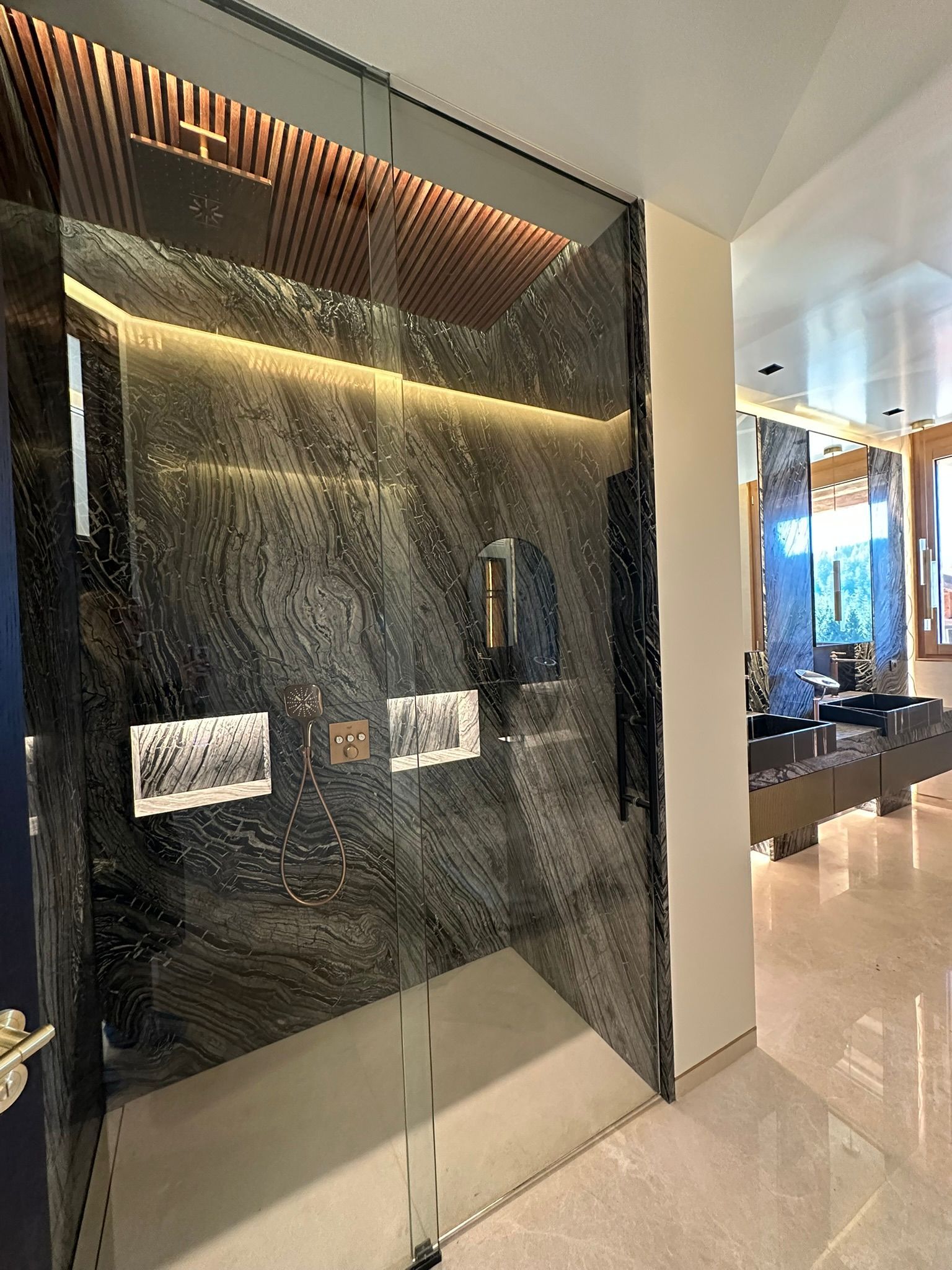 Une vitrine en verre adossée à un mur de pierre sombre. Décor intérieur avec des photographies éclairées par des plafonniers.