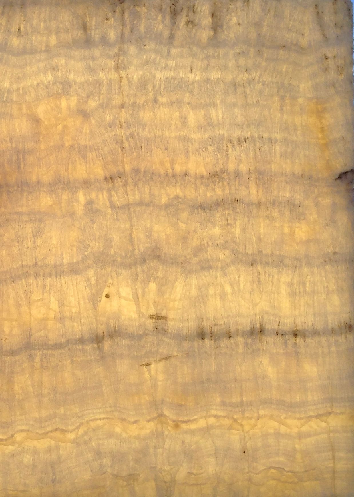 Pierre d'onyx en couches dorées et beiges, présentant des motifs et des textures naturels.