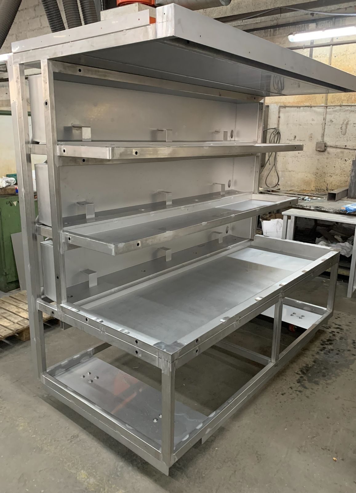 Un grand poste de travail en aluminium avec étagères et comptoir dans un environnement d'atelier.