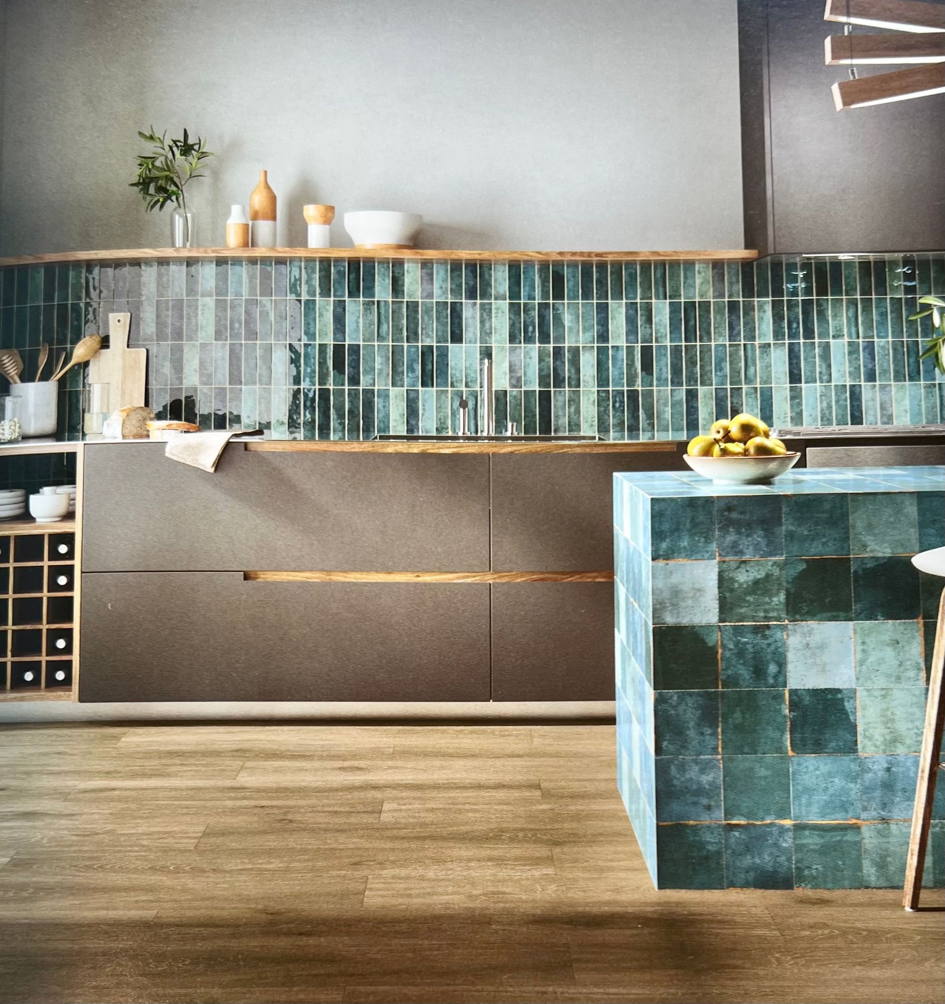 Cuisine moderne avec dosseret et îlot bleu sarcelle, armoires grises, comptoirs et planchers en bois.