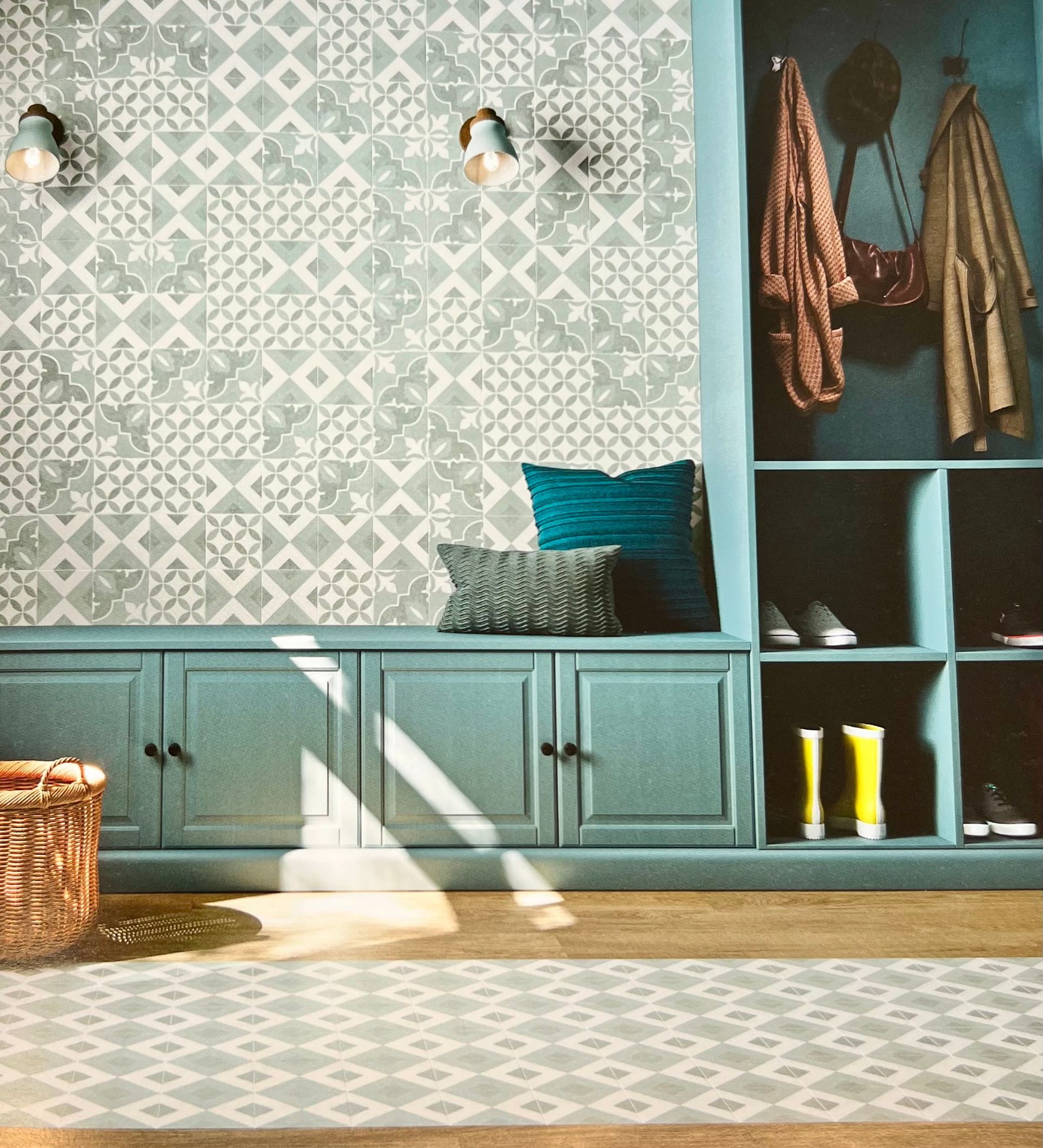 Entrée bleue avec papier peint à motifs, rangement intégré et banquette avec coussins.