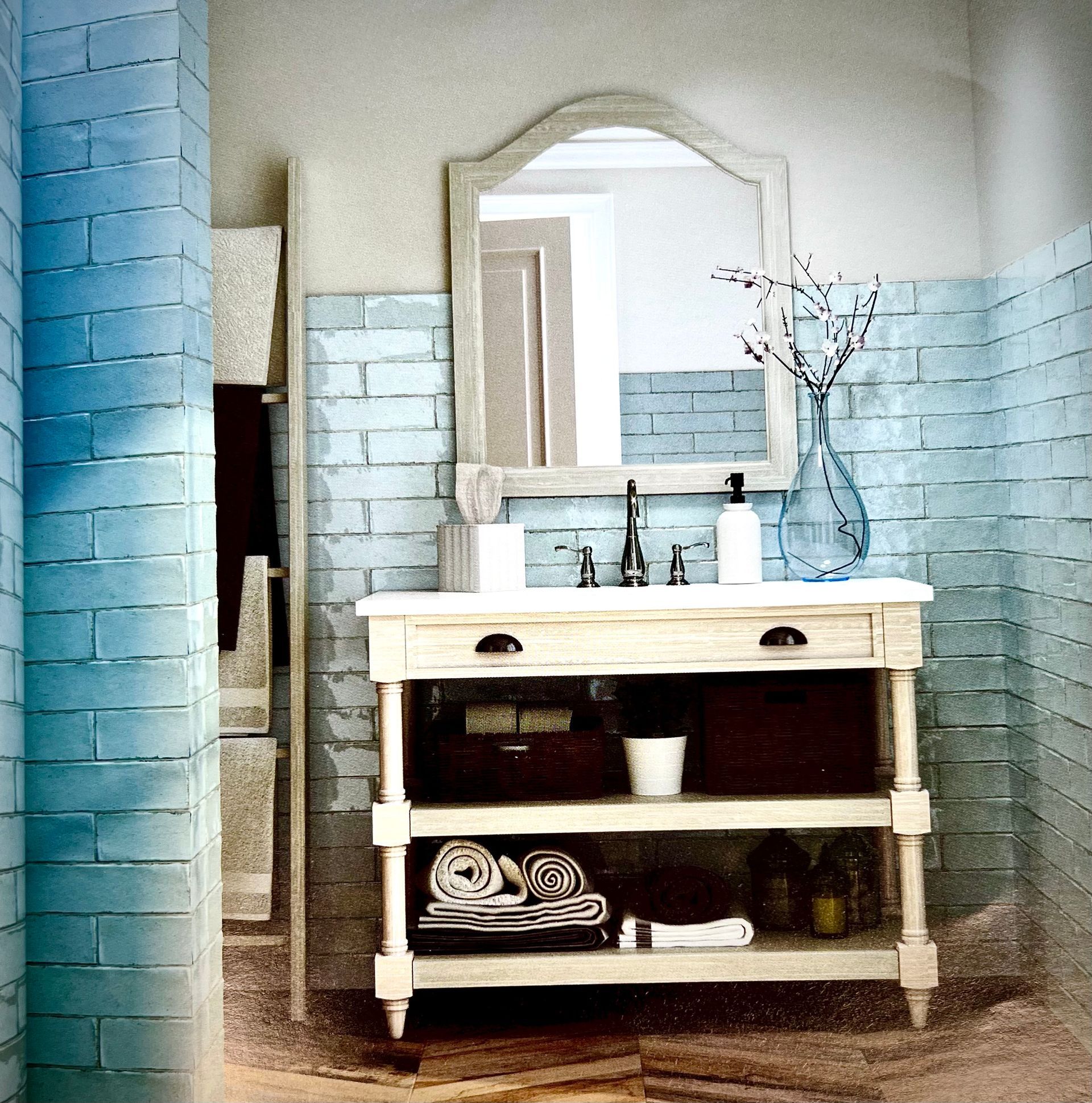 Salle de bain avec murs carrelés bleus, vanité blanche, miroir arqué et objets décoratifs.