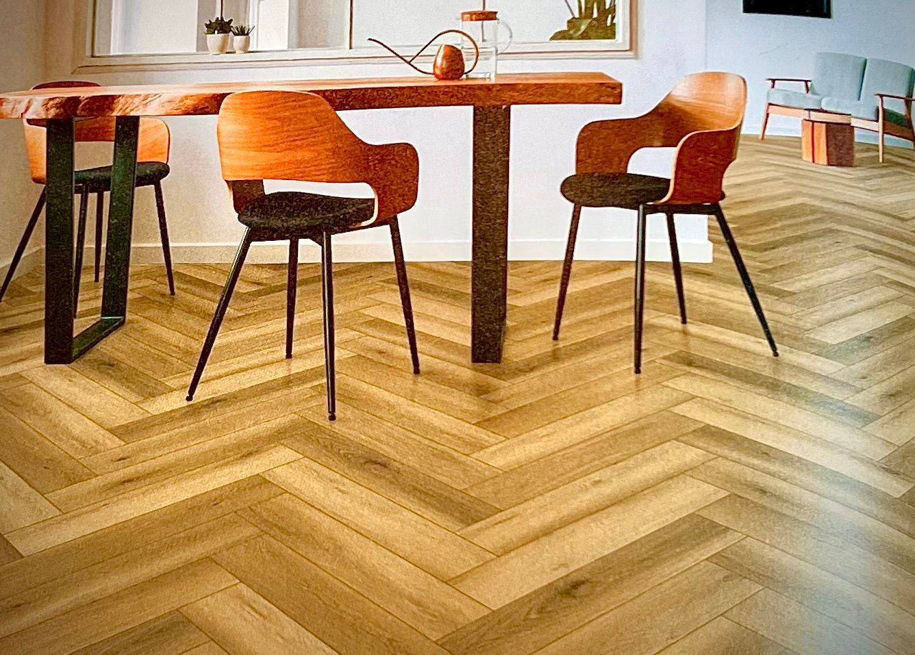 Plancher en bois à chevrons avec table à manger et chaises dans la chambre.