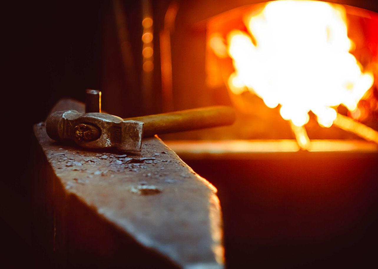 Marteau sur une enclume avec un feu de forge brillant en arrière-plan, orange brillant.