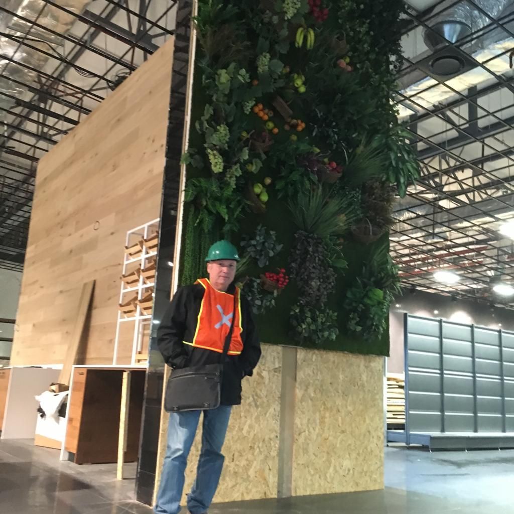 Un homme portant un gilet de sécurité et un casque de sécurité se tient à côté d'un grand mur.