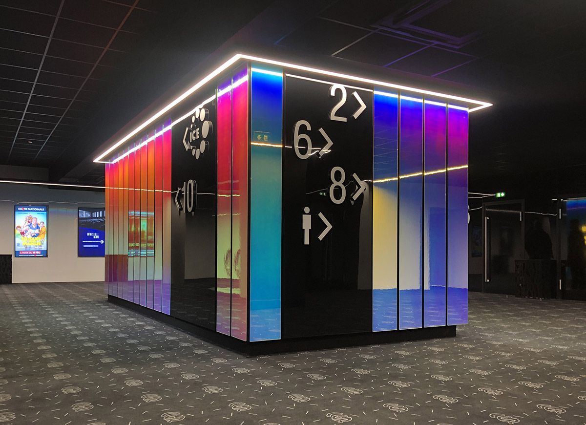 Un kiosque d'information coloré avec des panneaux directionnels dans le hall d'un théâtre.