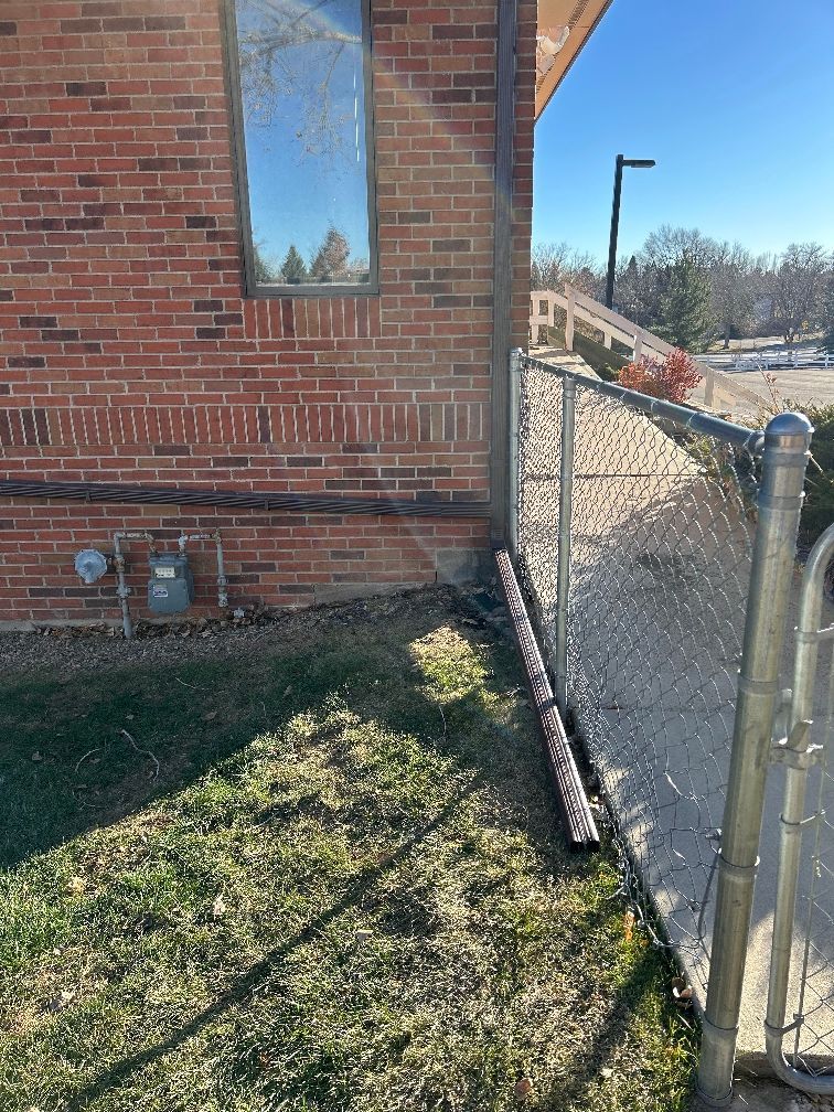 A chain link fence is sitting next to a brick building.