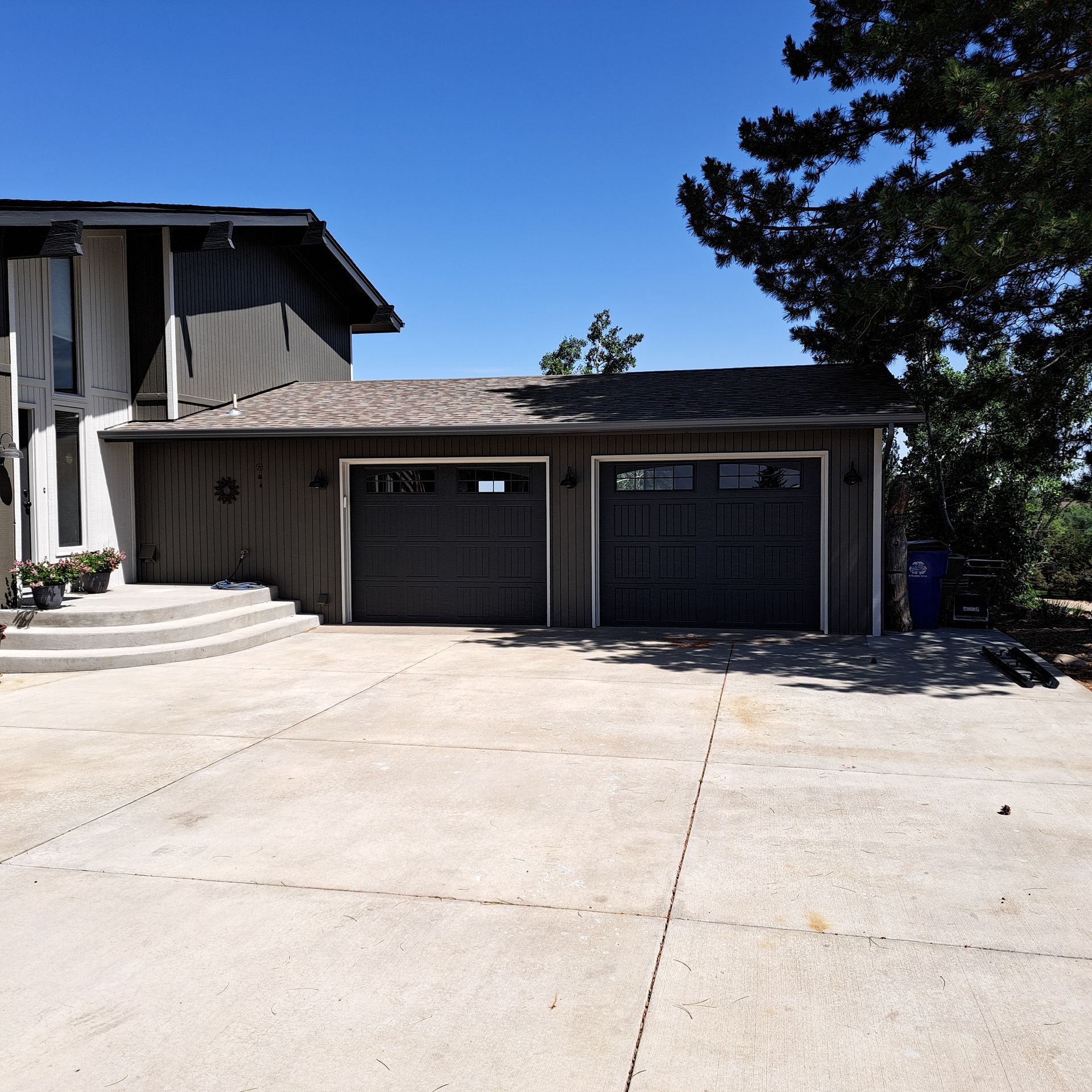 A house with two black garage doors on a sunny day