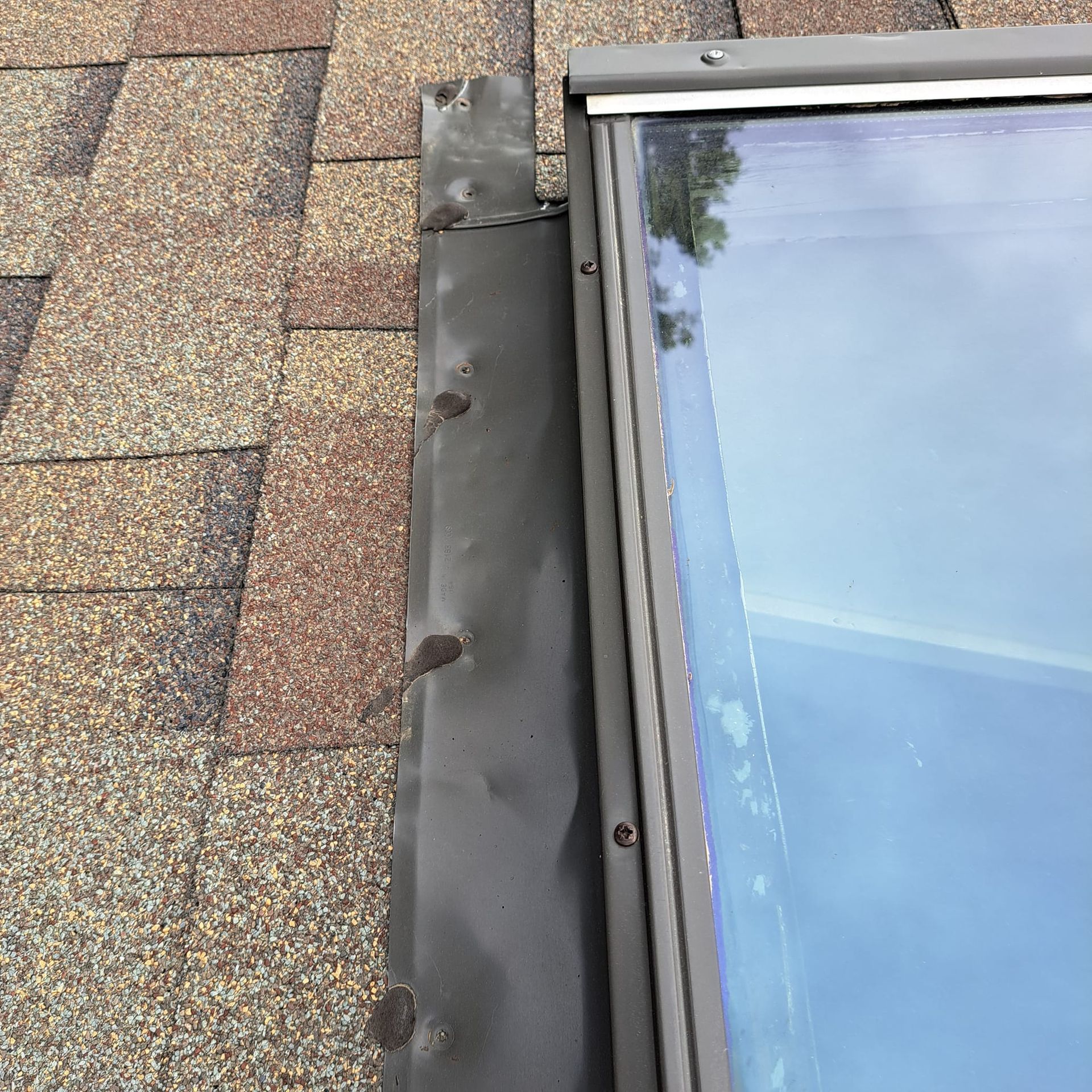 A skylight is sitting on top of a brick roof.