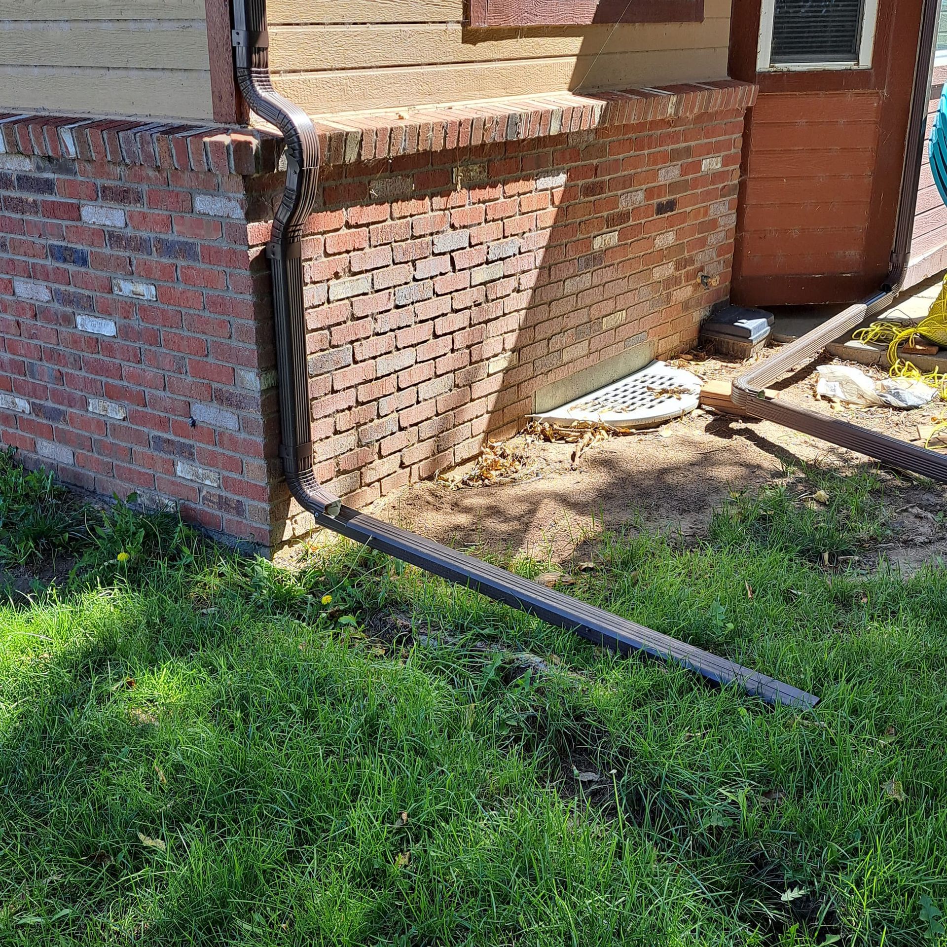 A brick house with a drain pipe on the side of it.