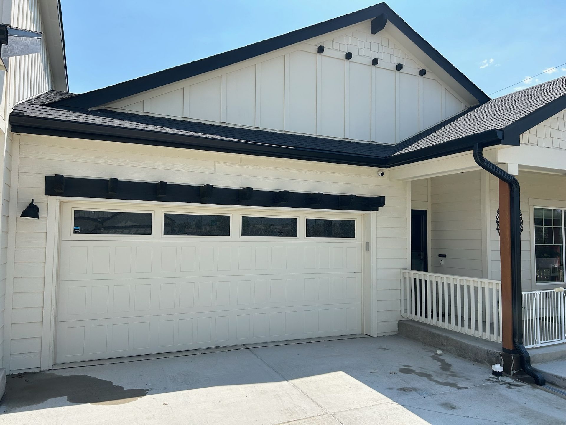 A white house with a black roof and a white garage door