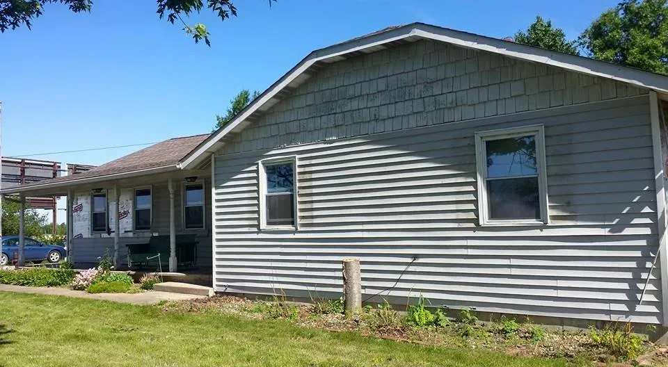 Gray single-story house with white trim and a covered porch on a sunny lawn