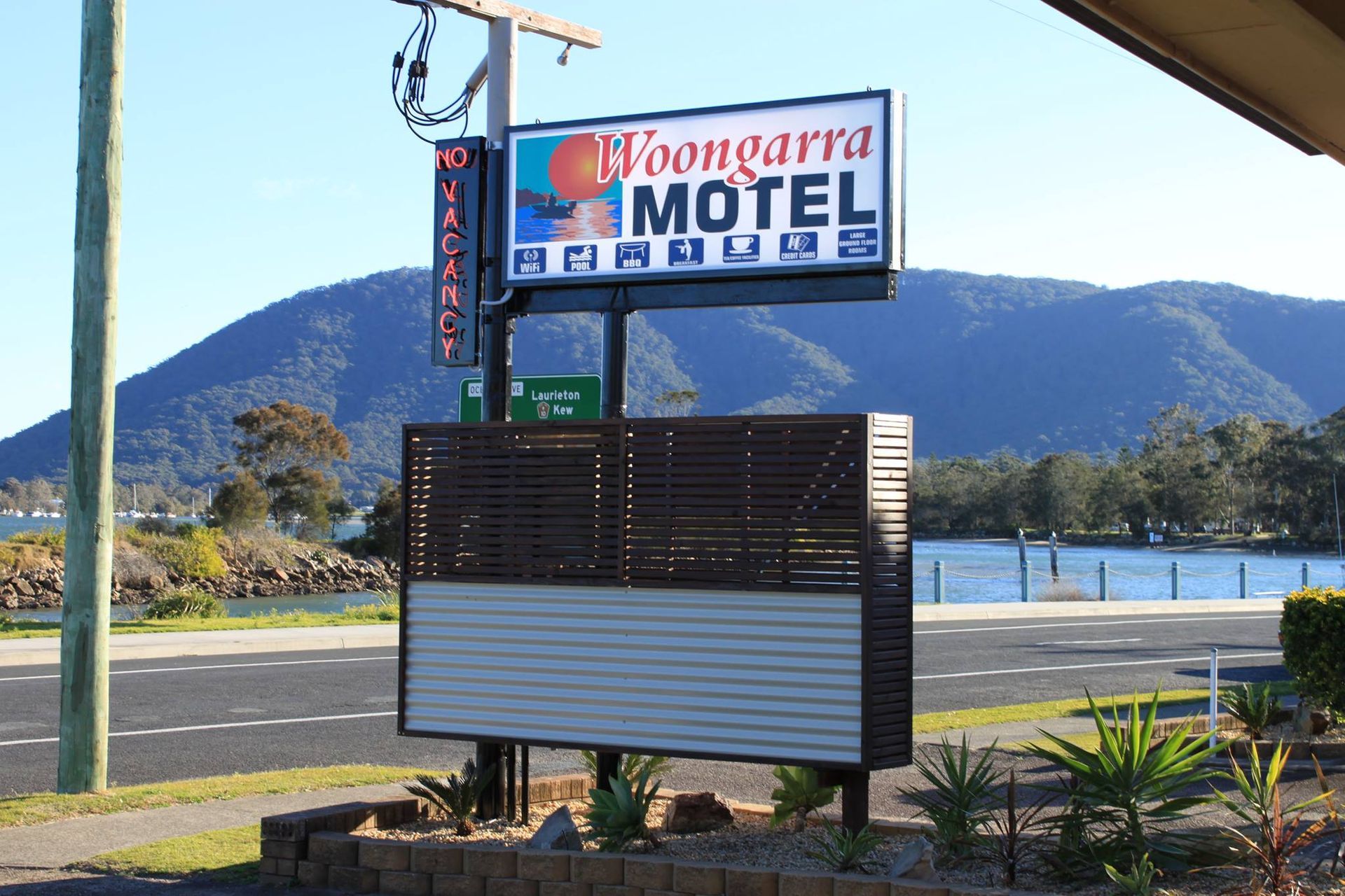 A Sign For A Motel With Mountains In The Background — Woongarra Motel In North Haven, NSW