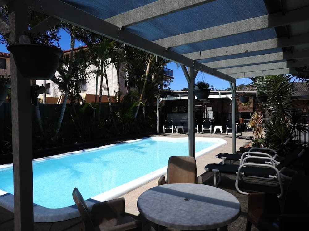 A Swimming Pool With A Table And Chairs Under A Canopy β Woongarra Motel In North Haven, NSW