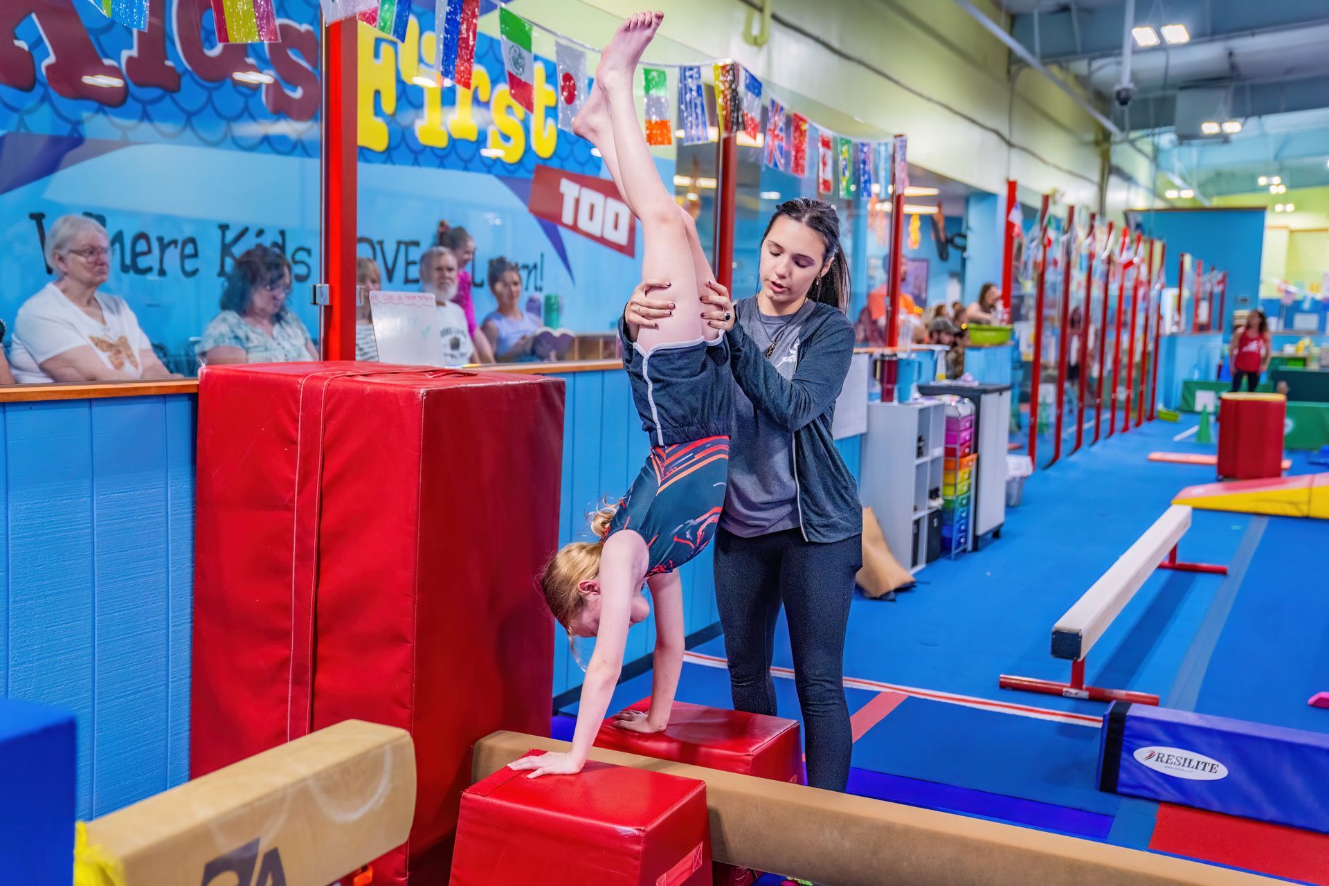 Girls Gym Jam class, teacher spotting handstand at Kids First Too