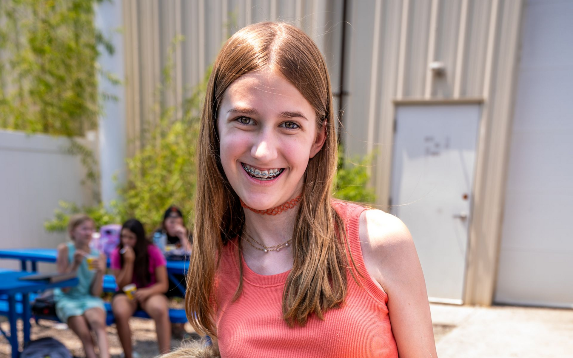 Young child jumping on a trampoline, arms raised, smiling; indoor gym setting.