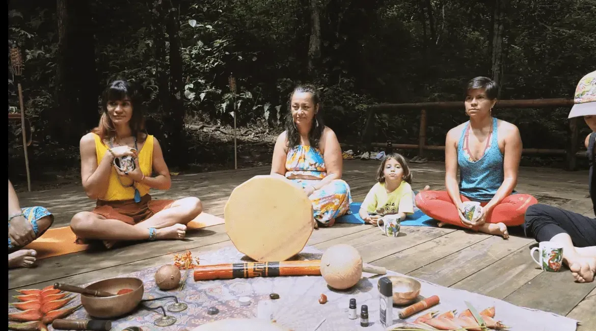 A group of women are sitting in a circle on a wooden deck.
